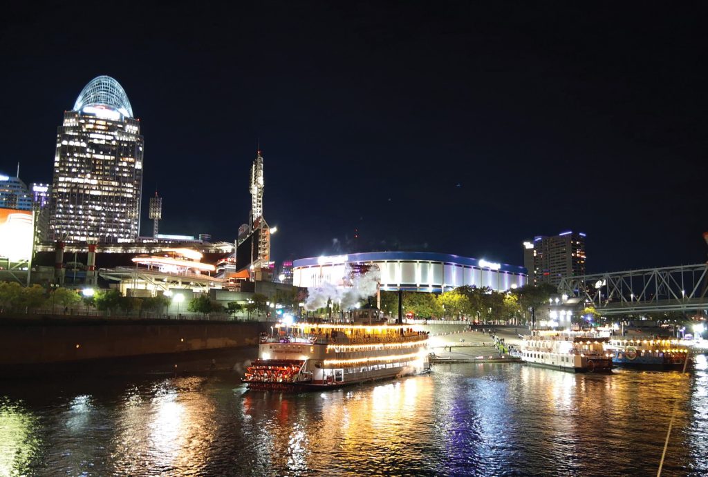 The Belle of Louisville (left) blows off steam on the Cincinnai riverfront during the America’s River Roots Festival. (Photo by Christi Kleiner)