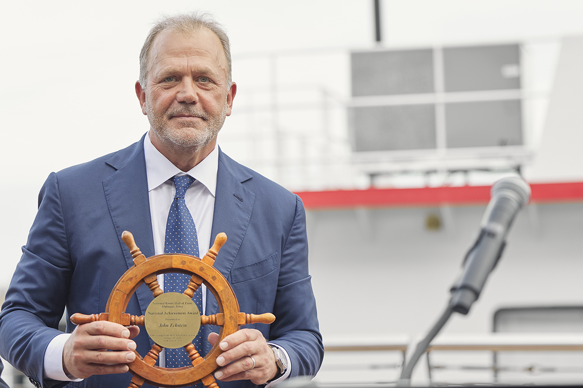 John Eckstein, executive chairman of Marquette Transportation, holds the National Rivers Hall of Fame Achieve Award with his namesake vessel, the John Paul Eckstein, in the background. (Photo by Brad Rankin)