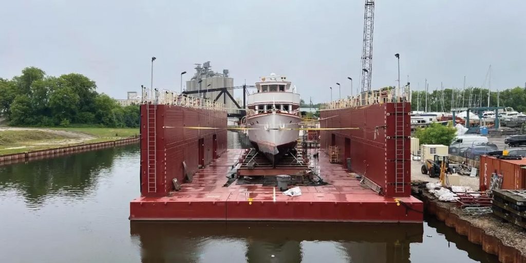 A vessel sits in American Ship & Dry-Dock Company’s modular drydock at the company’s shipyard, highlighting the system’s layout and working footprint. The dock’s sidewall and platform arrangement provide access and support for vessel repair work.