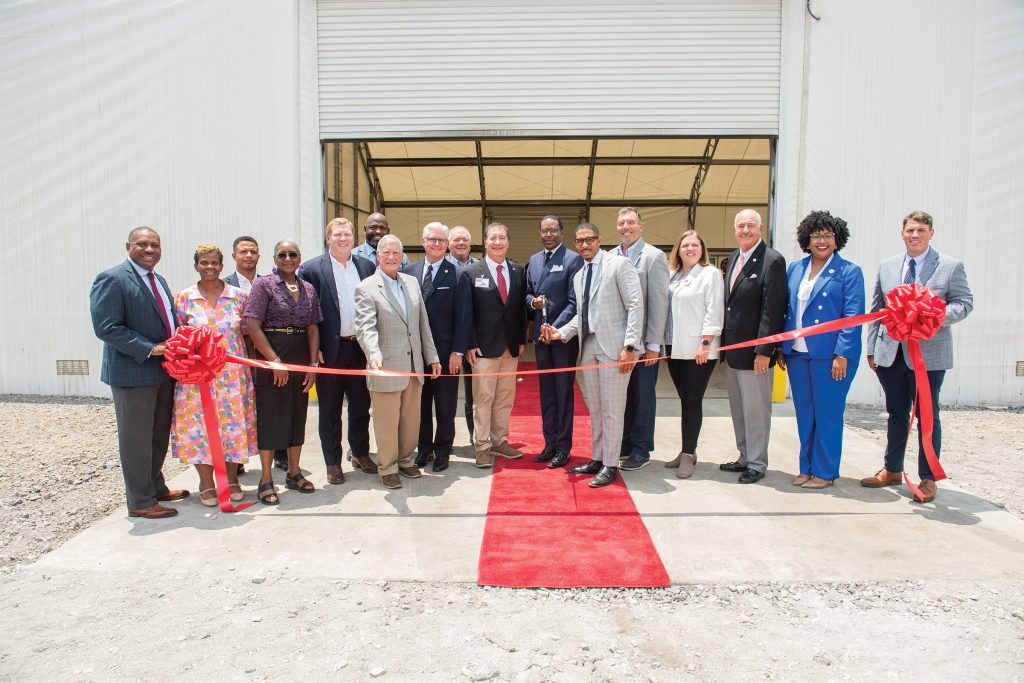 David Russell (front center) and officials gather for a ribbon-cutting ceremony at a new warehouse facility at the port. The project, developed with Watco, supports ongoing efforts to update port infrastructure and expand cargo-handling capacity.